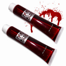 Two squeeze tubes of fake blood with white caps, labeled 'FAKE BLOOD' on silver labels, shown on a white background with a red blood splatter graphic.