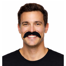 A smiling man with a black fake stick on handlebar moustache against a plain white background.