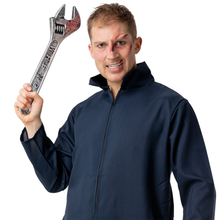 A man wearing a dark navy blue zip-up work jacket holds up a large silver wrench with a red scratch on the head, against a plain white background.