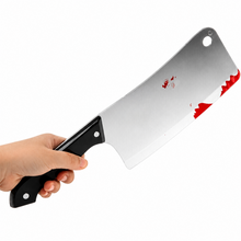 A novelty toy cleaver prop with a silver blade featuring red blood splatters and a black handle, held by a hand against a white background.