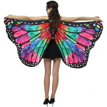 A woman shown from the back wearing a large butterfly wing costume accessory with bright multicolor wingspan panels outlined in black and white spots, against a plain white background.