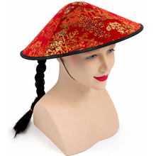 A red traditional-style conical hat with an ornate gold and multicolor floral pattern, displayed on a beige mannequin head with a black braid against a white background.