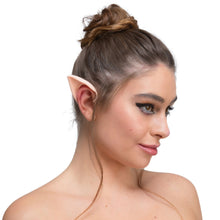 A woman with brown hair in a bun wearing a realistic pointed elf ear on her left ear, shown in profile against a plain white background.
