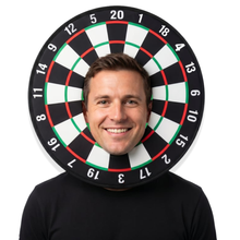 A smiling man wearing a black t-shirt with a realistic dartboard headpiece around his head, set against a plain white background.