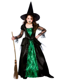 A child wearing a witch costume with a black pointed hat, black lace-trimmed dress, and green spiderweb-patterned lining, holding a broom against a plain white background.