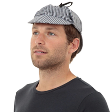 A man wearing a Sherlock Holmes-style deerstalker hat with a black and white houndstooth pattern, photographed against a solid white background.
