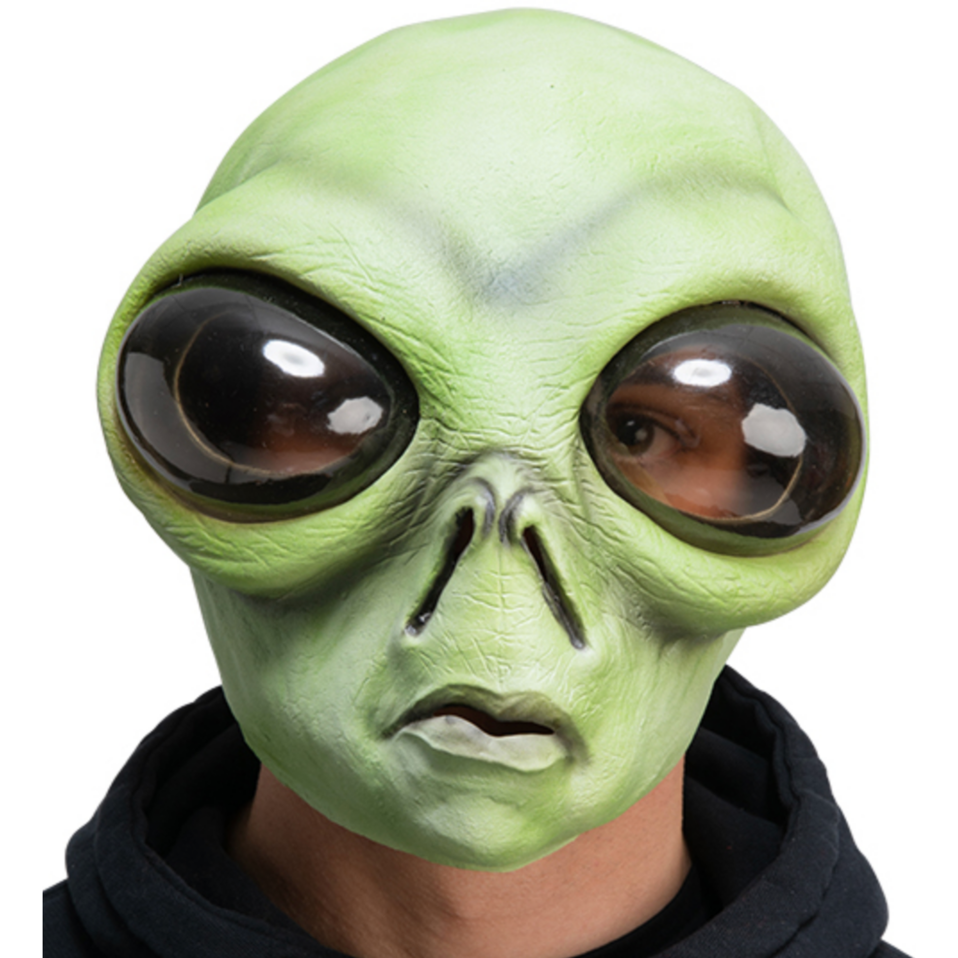 A green alien mask with large glossy black and brown eyes, worn by a person in a black hoodie against a plain white background.