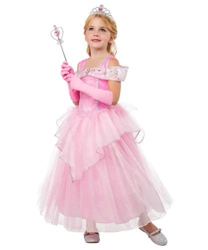 A young girl modeling a pink princess costume consisting of a tiered tulle dress, long pink gloves, a silver tiara, and holding a matching wand, set against a plain white background.