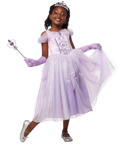 A young girl modeling a lavender princess costume dress with a tiara, holding a wand, and wearing purple gloves and silver shoes against a plain white background.