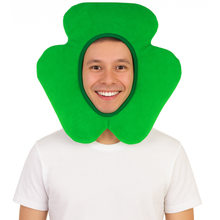 A man wearing a bright green shamrock-shaped costume headpiece over his head, paired with a white t-shirt, against a plain white background.