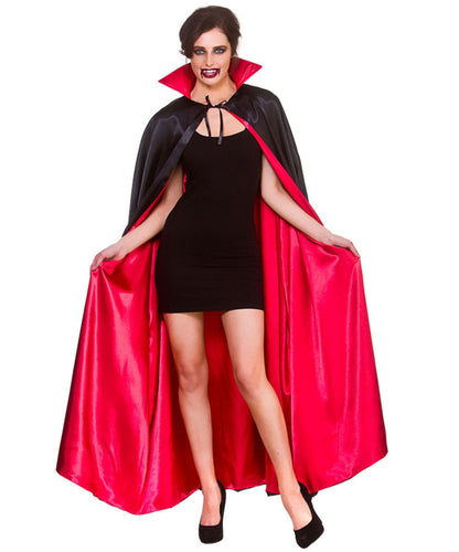 A woman modeling a vampire costume consisting of a black dress, a black cape with a bright red lining, and a red inner collar, against a plain white background.