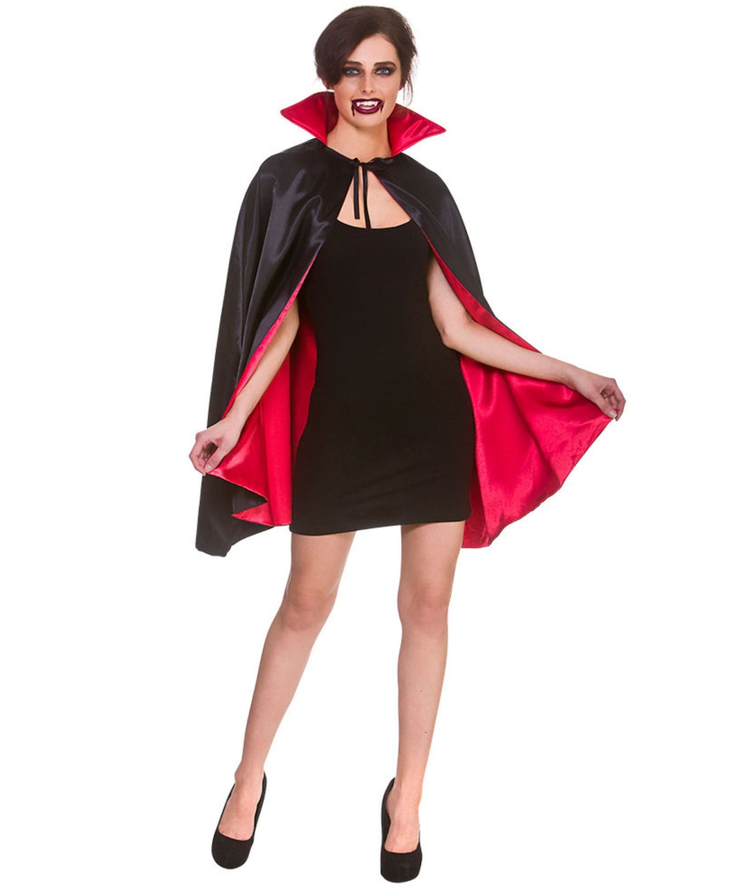 A woman modeling a vampire costume consisting of a black satin cape with a bright red inner lining, worn over a black mini dress and black heels, against a plain white background.
