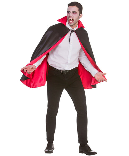 A man modeling a vampire costume consisting of a black cape with a bright red lining, worn over a white dress shirt, black trousers, and black dress shoes, against a plain white background.