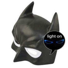 Black Batman-style mask with pointed ears and white eye cutouts, shown on a white background with a circular callout that says 'light on' and indicates glowing blue eyes.
