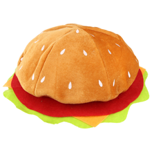 A plush hat shaped like a hamburger, featuring a brown velvet bun with white seed details, a red felt layer, yellow cheese, and green lettuce, shown on a plain white background.