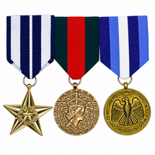 Three military-style medals with gold-toned metal ribbons and bars are displayed side by side on a plain white background. The left medal has a blue, white, and navy striped ribbon with a gold star pendant.
