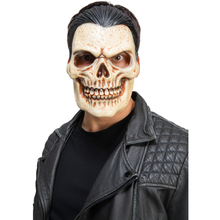 A man wearing a realistic skull mask with a stitched expression, black hair, and a black leather jacket over a black shirt, photographed against a plain white background.