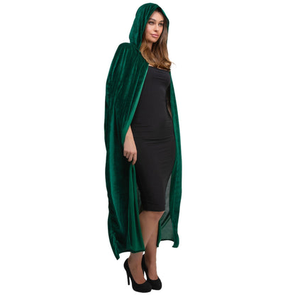 A woman modeling a long, dark green velvet hooded cloak or cape over a black dress and black heels, photographed against a plain white studio background.