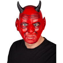 A person wearing a red devil mask with black horns, blue-gray eyes, and a black shirt, photographed against a plain white background.