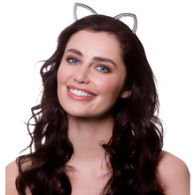 A smiling woman with long dark wavy hair wearing a silver cat-ear headband with sparkling rhinestone details, set against a plain white background.