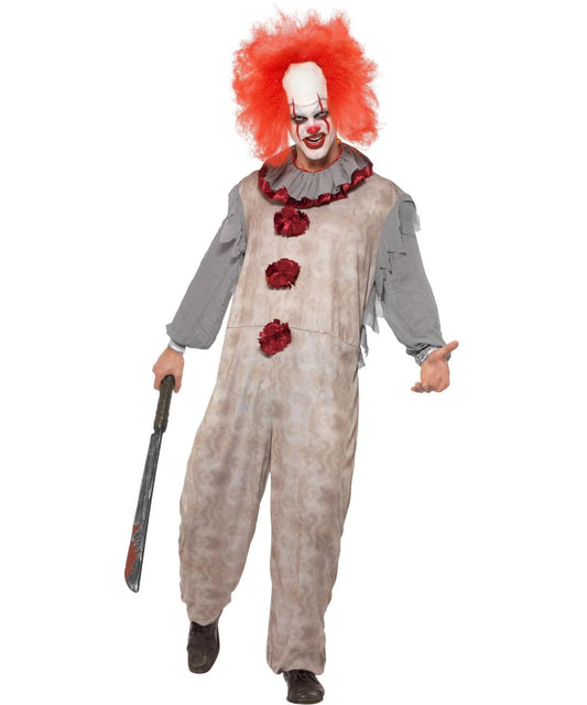 A person modeling a horror clown costume against a plain white background, holding a toy knife. The costume includes a distressed beige jumpsuit with red flower accents, a gray ruffled collar and sleeves, a red wig, and a white face mask with red clown makeup.