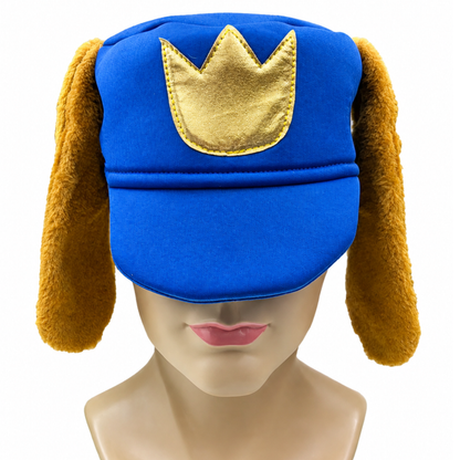 A royal blue hat with long brown floppy ear flaps and a gold crown applique on the front, displayed on a mannequin head against a white background.