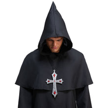 man wearing a black robe wearing a decorative gothic cross pendant with red gemstones on a white background