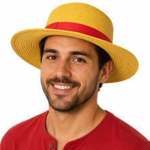 A man wearing a yellow woven straw boater hat with a red band, paired with a red henley shirt, against a plain white background.
