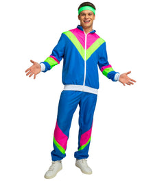 A man modeling a 1980s-style two-piece tracksuit costume with a bright blue base and bold pink and neon green chevron accents, along with a matching green headband and white sneakers, on a plain white background.