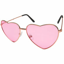 Oversized heart shaped sunglasses with a rose gold metal frame, vibrant pink lenses, and black temple tips, shown in profile against a white background. facing forward at an angle