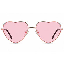 Oversized heart shaped sunglasses with a rose gold metal frame, vibrant pink lenses, and black temple tips, shown in profile against a white background. facing forward 