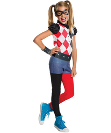 A young girl modeling a Harley Quinn costume against a plain white background. The costume features a red, white, and black harlequin pattern top with black puffed sleeves, a black mask, blue denim shorts, a black faux belt with silver studs, black leggings on one leg, bright red leggings on the other leg, and blue high-top sneakers.