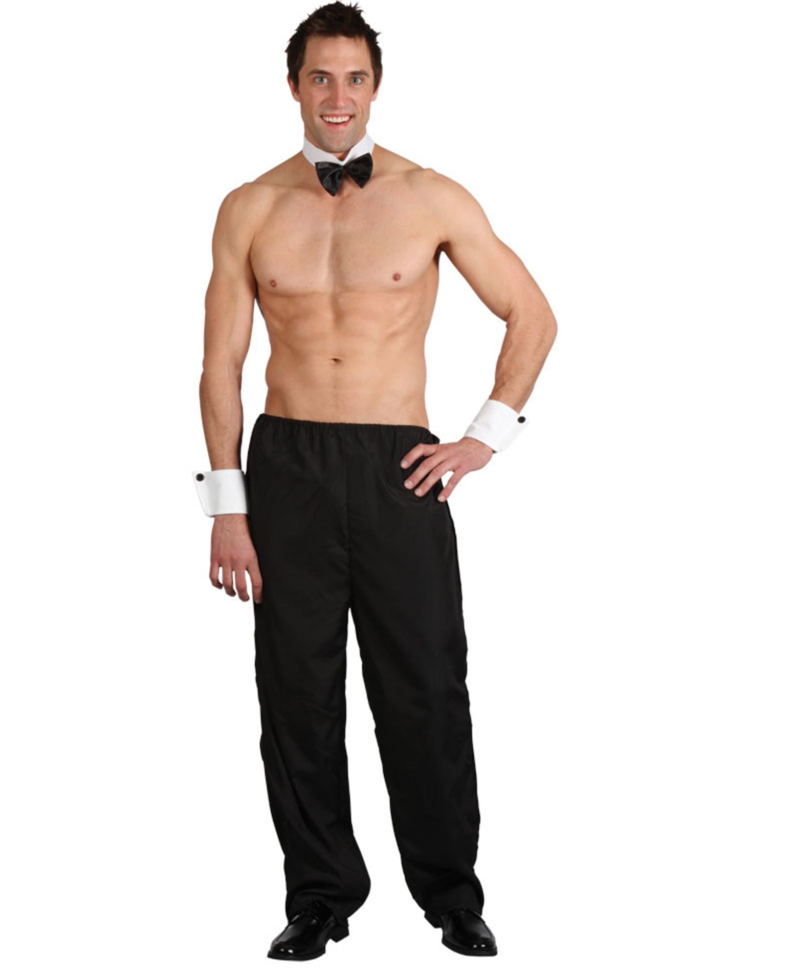 A shirtless male model wearing a black tuxedo-style pants outfit with a black bow tie, white cuffs, and black dress shoes against a plain white background.