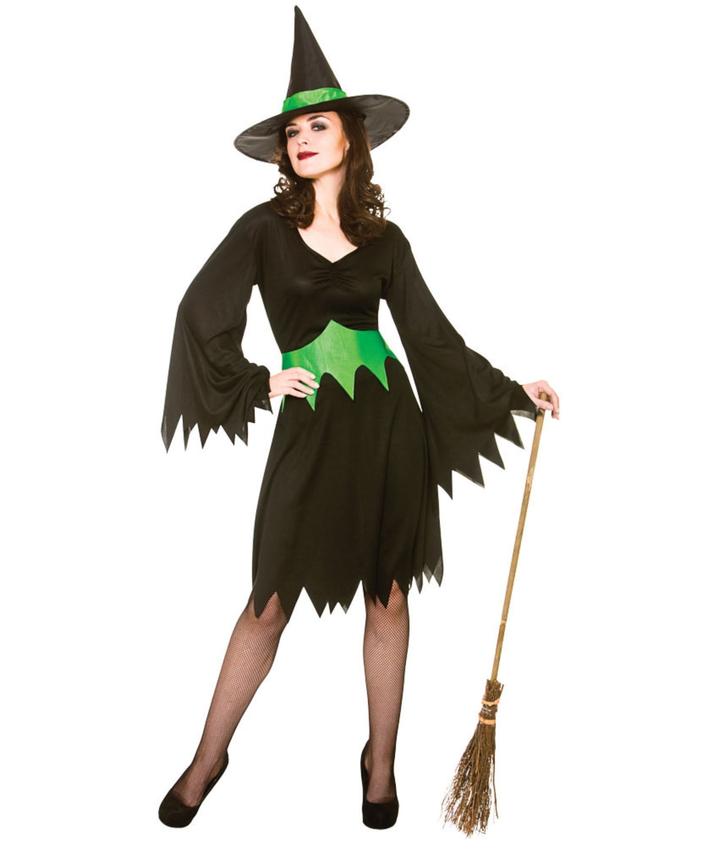 A woman modeling a witch costume consisting of a black dress with green accents, a black pointed witch hat with a green band, and holding a small broomstick against a plain white background.