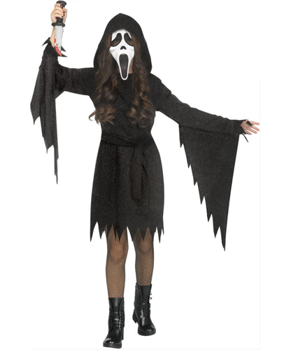 A child modeling a Ghostface-style costume on a plain white background, wearing a black hooded robe with jagged sleeves and hem, a white-and-black mask, long dark hair, black tights, black boots, and holding a knife prop.